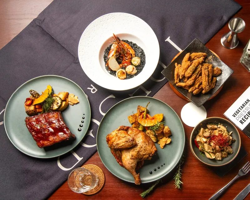 Dishes at Trésor Bistro: squid ink risotto, charcoal-grilled pork ribs, roast half chicken and fried chicken tenders